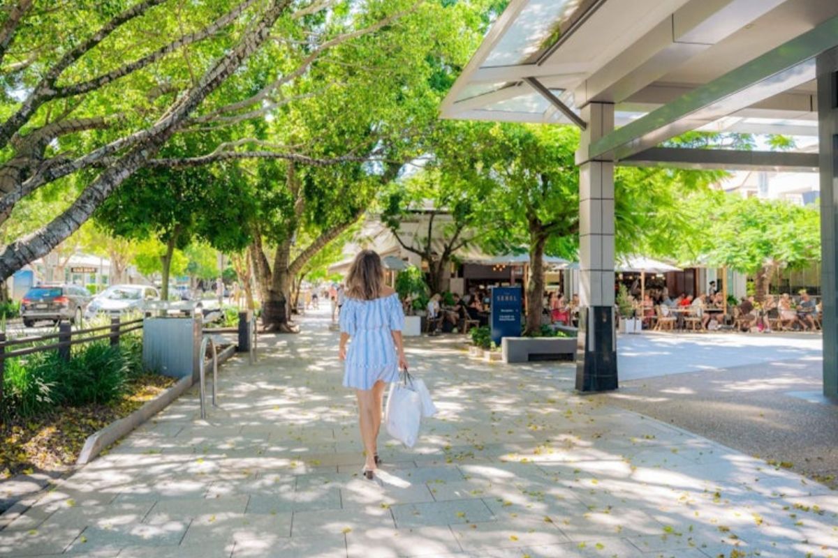 Woman walking along Hastings Street Noosa on a sunny summer day