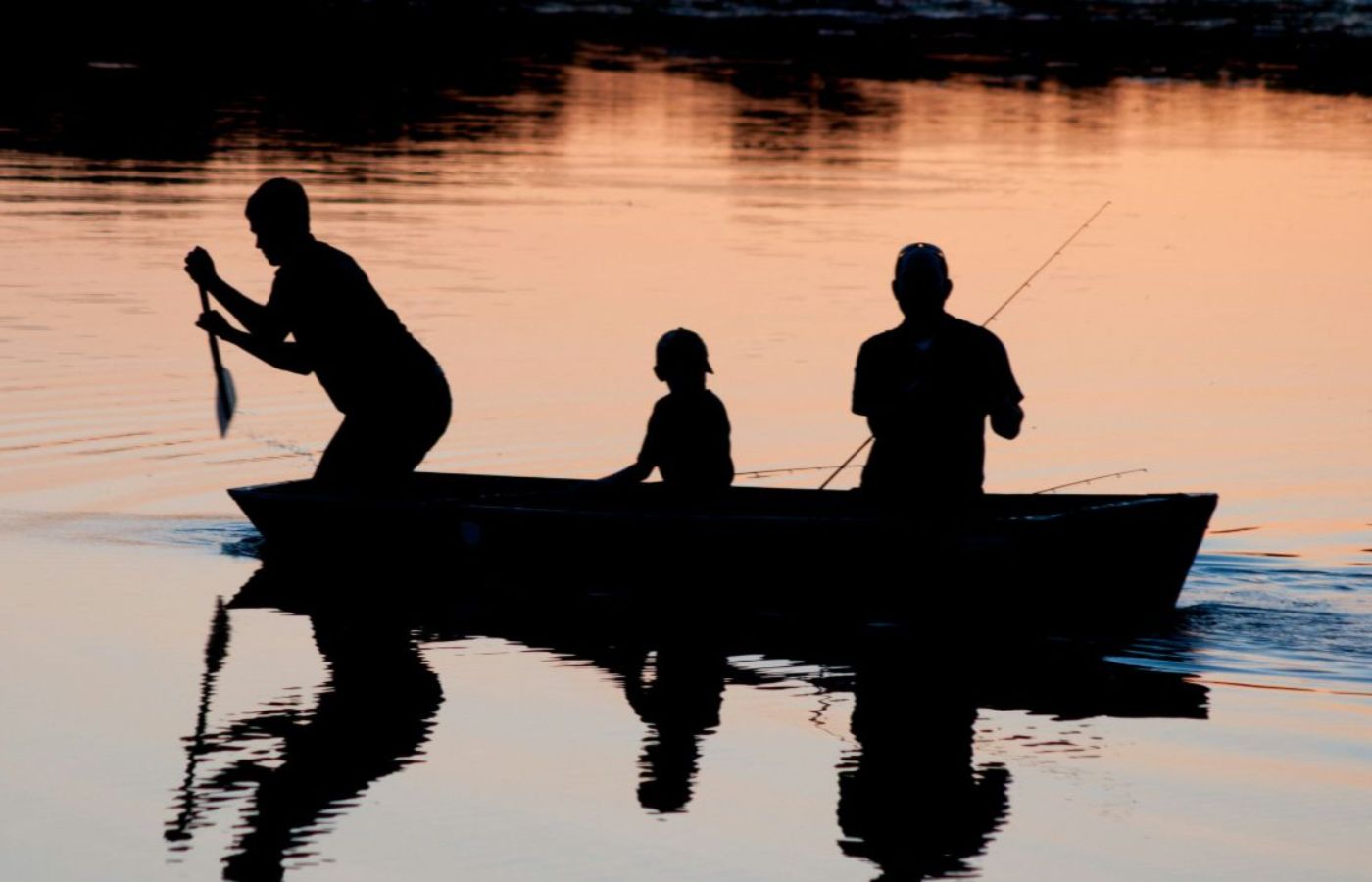 Family fishing on a calm Noosa waterway at sunset in a small boat